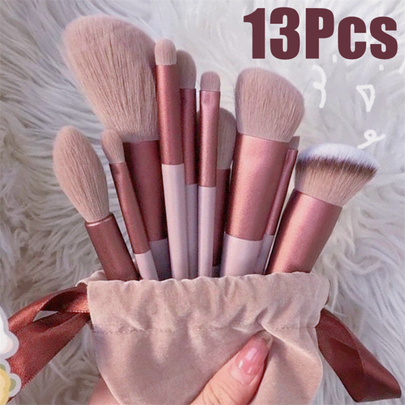Set of 13 pink and rose gold makeup brushes with soft bristles in a beige pouch on white fur background