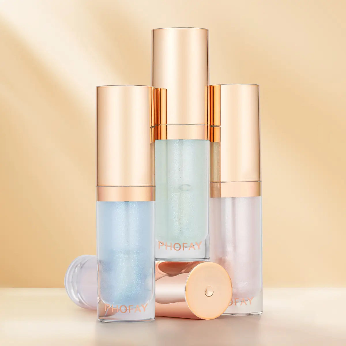 four lip oil bottles with gold caps on a beige background