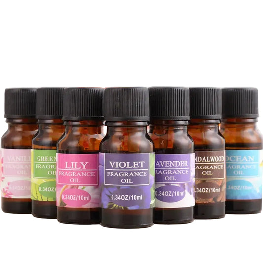 Row of fragrance oil bottles with colorful labels on a wooden surface.
