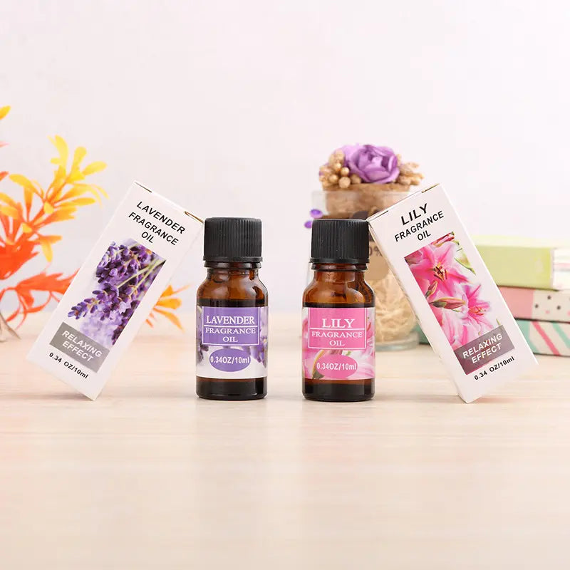 Two fragrance oil bottles with labels for lavender and lily scents on a light surface.