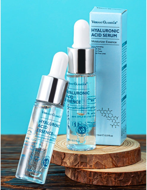 Vibrant Glamour Hyaluronic Acid Serum bottles with dropper and packaging on wood slices, blue background
