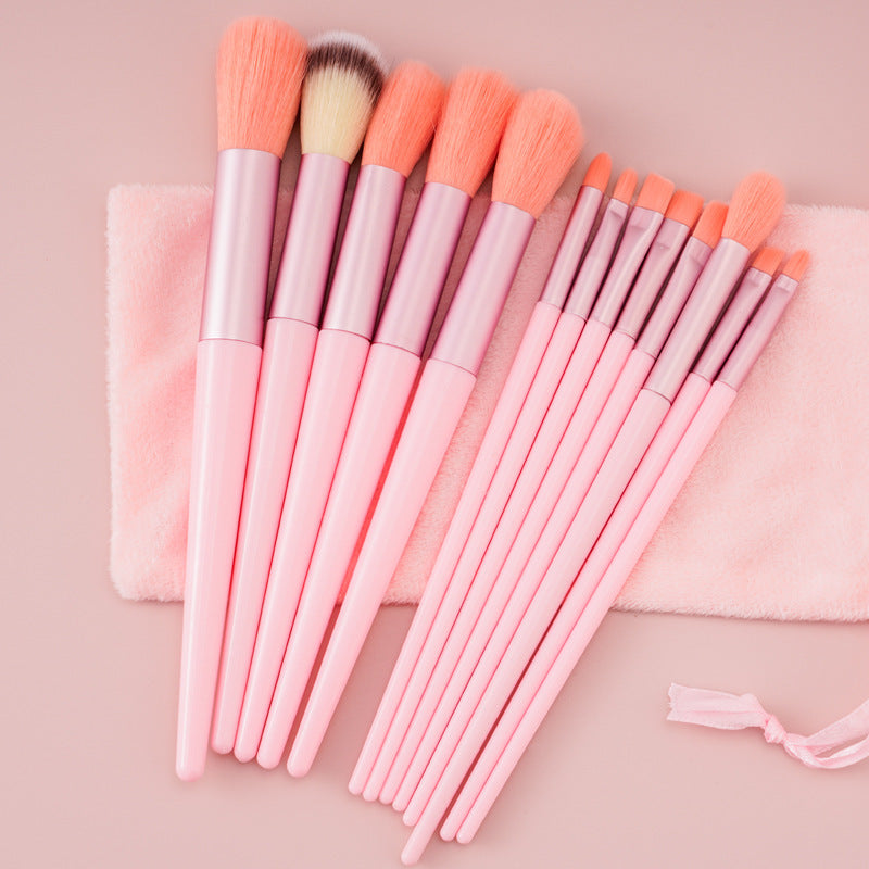 Set of pink makeup brushes with soft bristles on a pink cloth and pale pink background