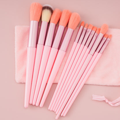 Set of pink makeup brushes with soft bristles on a pink cloth and pale pink background