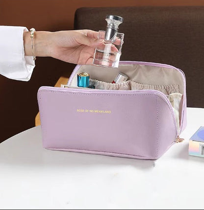 Purple cosmetic bag with makeup items on a white surface