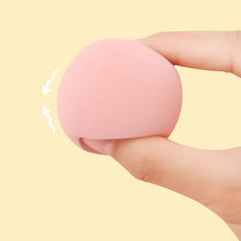 Hand squeezing soft pink stress ball against light beige background