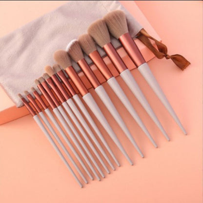 Set of 12 white handle makeup brushes with rose gold ferrules on peach background with white pouch